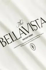 Remera oversized blanca de punto de algodón, con cuello redondo, mangas cortas y estampa tipográfica frontal con la inscripción "The Bellavista".