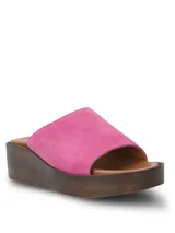 Sandalia tipo slide con capellada de gamuza en color fucsia, con plataforma de poliuretano efecto madera y plantilla de cuero marrón.