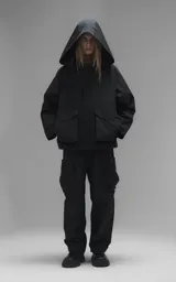 Campera técnica liviana de microfibra negra con acabado mate, capucha ajustable, cierre frontal oculto bajo solapa, bolsillos frontales con solapa y cordón ajustable en la cintura.