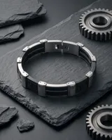 Pulsera de diseño moderno compuesta por una banda central de goma negra flanqueada por piezas de acero inoxidable con grabado de guarda griega.