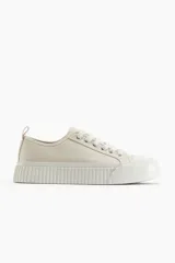 Zapatillas deportivas de lona color crudo, con cordones y suela de goma con diseño.
