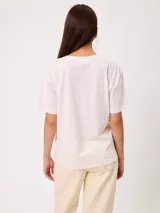 Remera de algodón marca Rusty, color blanco, de corte holgado, con cuello redondo, mangas cortas y estampado frontal colorido de temática tropical.