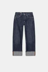 Pantalón de jean de tiro medio con corte recto y cinco bolsillos. Presenta un acabado con dobladillo ancho en el bajo y cierre frontal con botones metálicos.