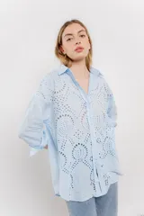 Camisa celeste de algodón liviano con bordado calado tipo broderie, manga larga con puño angosto y botones al frente.