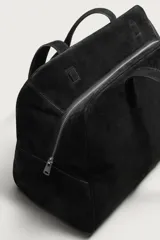 Bolso de viaje de diseño minimalista confeccionado en piel con acabado serraje. Cuenta con compartimento principal con cierre de cremallera e imanes, interior con bolsillos organizadores y doble asa de mano en piel.