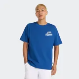 Remera de algodón azul vibrante, corte holgado, con cuello redondo y un pequeño estampado del logo de New Balance en tipografía cursiva blanca en el pecho.