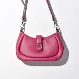 Bandolera fucsia de cuero sintético con correa larga regulable y cierre con broche metálico.
