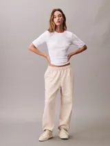 Pantalón tipo jogger de Calvin Klein en color beige, confeccionado en tejido de felpa de mezcla de algodón. Presenta cintura elástica con cordón ajustable, bolsillos laterales y bajos con puños de canalé. Incluye un discreto monograma de la marca estampado en la pierna.