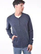 Campera tejida color beige melange, con cierre frontal completo y cuello redondo. Presenta un tejido texturizado de punto fino y bolsillos delanteros tipo ojal.