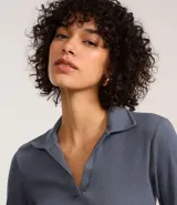 Blusa de manga larga confeccionada en tejido rib de algodón con elastano. Presenta un diseño ajustado al cuerpo con cuello polo y escote en V.