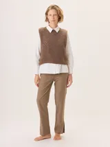 Chaleco de punto en color marrón, con diseño sin mangas, cuello redondo y textura suave. Presenta un calce holgado y corto, ideal para superponer sobre otras prendas.