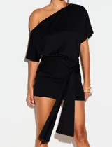 Vestido corto negro con escote asimétrico de un solo hombro y mangas cortas. Presenta un diseño ajustado con un nudo lateral y tiras colgantes en la cintura.