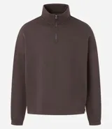 Buzo de corte holgado tipo ballon, color marrón oscuro, con cuello alto y cierre frontal parcial. Presenta mangas largas con puños elásticos y cordón ajustable en el ruedo.