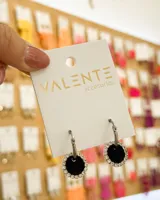 Aros colgantes plateados con forma de argolla, con dije circular de terciopelo negro y borde de strass. El material del aro es acero.