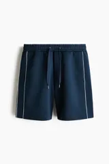 Short azul marino de punto con leve brillo, cintura elástica con cordón de ajuste y ribetes laterales en color blanco.