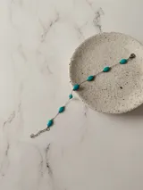 Pulsera de acero quirúrgico con cadena fina y piedras ovaladas de color turquesa intercaladas.