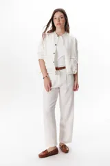 Pantalón de lino color marrón oscuro, tiro alto, corte recto y holgado, con pinzas delanteras y pespuntes a contratono en blanco.