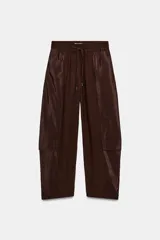 Pantalón de tiro medio con cintura elástica ajustable mediante cordón. Presenta un diseño de pernera holgada que se estrecha hacia el tobillo, con paneles laterales en tejido satinado y bolsillos cargo laterales.