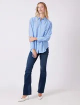 Camisa de algodón con estampado de rayas verticales finas en color azul claro. Tiene cuello con solapa, escote en V y cierre frontal con botones.