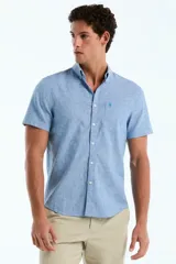 Camisa de manga corta de lino y algodón color celeste melange, con cuello abotonado, cierre frontal de botones y bolsillo ojal en el pecho con el logo bordado.