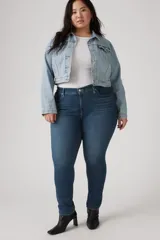 Pantalón de jean azul oscuro, tiro medio, corte ajustado y largo hasta el tobillo.