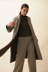 Tapado con cuello solapa y corte recto, color gris. Cierre frontal con botones ocultos, tajos laterales y bolsillos escondidos en corte lateral. Con forro. Tela 100% lana fina sin teñir, diseñada exclusivamente por Don Baez. Hecha 100% en Uruguay.