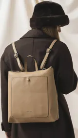 Mochila de diseño moderno y funcional, confeccionada en símil cuero con textura granulada. Cuenta con un bolsillo frontal con broche, cierre principal superior, manija superior y correas ajustables. Incluye logo de la marca grabado en el frente.