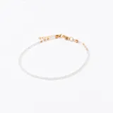 Pulsera de cuentas facetadas color blanco opalescente con detalles de pequeñas cuentas doradas y cierre de mosquetón dorado con cadena de alargue.