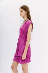 Vestido corto de color fucsia, confeccionado en tela con efecto crinkle. Presenta un diseño sin mangas con escote en V profundo tanto en el frente como en la espalda, cintura marcada y falda con volados. Incluye tiras de ajuste en los hombros con terminaciones metálicas.