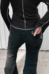 Jean wide leg color negro, de tiro medio-alto, con costuras verticales frontales y tajos en el ruedo.