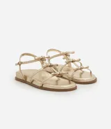 Sandalia plana dorada con tiras finas y detalle de lazos.