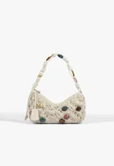 Cartera baguette de cuero color beige con diseño trenzado tipo red y apliques de cuentas de colores y formas metálicas en el cuerpo y en la manija. Cuenta con cierre superior y etiqueta colgante de la marca.