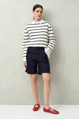 Bermuda negra de tiro medio con silueta recta y largo a la altura de la rodilla. Presenta bolsillos laterales y traseros, y costuras visibles.