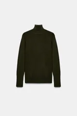 Jersey de punto liso en color beige, con cuello alto y manga larga con detalle de botones metálicos en los puños.