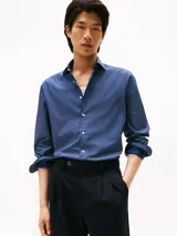 Camisa de manga larga Tommy Hilfiger con corte slim, confeccionada en algodón. Presenta un estampado de micro puntos en tonos azules y blancos, cuello clásico y cierre frontal con botones. Incluye el logo de la marca bordado en el pecho.