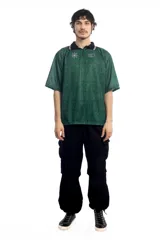 Remera deportiva verde con cuello polo negro con detalles de líneas blancas, mangas cortas con ribete negro y estampado con el logo de la marca en el pecho.