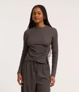 Blusa gris oscuro texturizada de poliéster y elastano, con cuello alto, mangas largas y detalle de fruncido lateral.