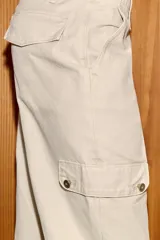 Pantalón capri de tiro medio con bolsillos cargo laterales, cierre frontal con cremallera, botón metálico y cordón ajustable en la cintura.