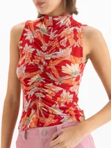 Top al cuerpo sin mangas con escote alto tipo polera y detalle de frunce en el centro delantero. Presenta un estampado full print de flores hibiscos en tonos rojos y naranjas sobre base celeste.