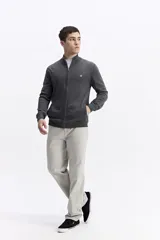 Campera tejida de algodón en color gris, con cierre frontal completo, cuello alto y puños acanalados. Presenta un pequeño logo bordado en el pecho.