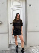 Remerón negro de encaje con mangas cortas, cuello redondo y corte holgado. Incluye un cinturón con apliques metálicos.