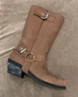 Bota de cuero marrón con caña alta y estribo desmontable.