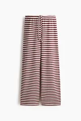 Pantalón de punto suave, de piernas amplias y corte holgado, con diseño a rayas horizontales en color bordó y blanco. Cuenta con cintura elástica y cordón ajustable.