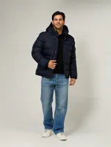 Campera puffer azul marino con diseño acolchado, capucha ajustable, cierre frontal de cremallera y bolsillos laterales con cierre. Presenta logo bordado en el pecho de Tommy Hilfiger.
