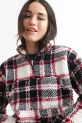 Buzo crop de corderito con estampado a cuadros en blanco, negro y rojo, con cierre de cremallera en el cuello.