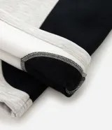 Pantalón de jogging confeccionado en algodón y poliéster, con diseño de paneles laterales en contraste de color negro. Presenta cintura elástica con cordón ajustable y bolsillos laterales.