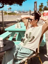 Sweater de punto color beige con mangas ranglan color marrón y aplique de cuero con forma de cactus en el frente.