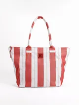 Bolso tipo tote grande, resistente al agua, con diseño de rayas verticales rojas y blancas. Cuenta con asas largas de hombro, cierre superior y parche de cuero con logo grabado. Incluye neceser transparente a juego con base y detalles a rayas.