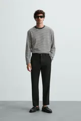 Pantalón chino de corte slim fit, confeccionado en tejido elástico. Presenta bolsillos frontales, bolsillos traseros de vivo con botón y cierre frontal con cremallera y botón.
