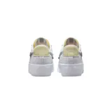 Championes Nike Blazer Low Platform Next Nature, de diseño bajo con plataforma. Presentan un cuerpo de lona blanca con detalles en cuero texturizado, un swoosh lateral en color celeste y un pequeño parche bordado decorativo. Incluyen refuerzos en la puntera y el talón en tonos neutros.
